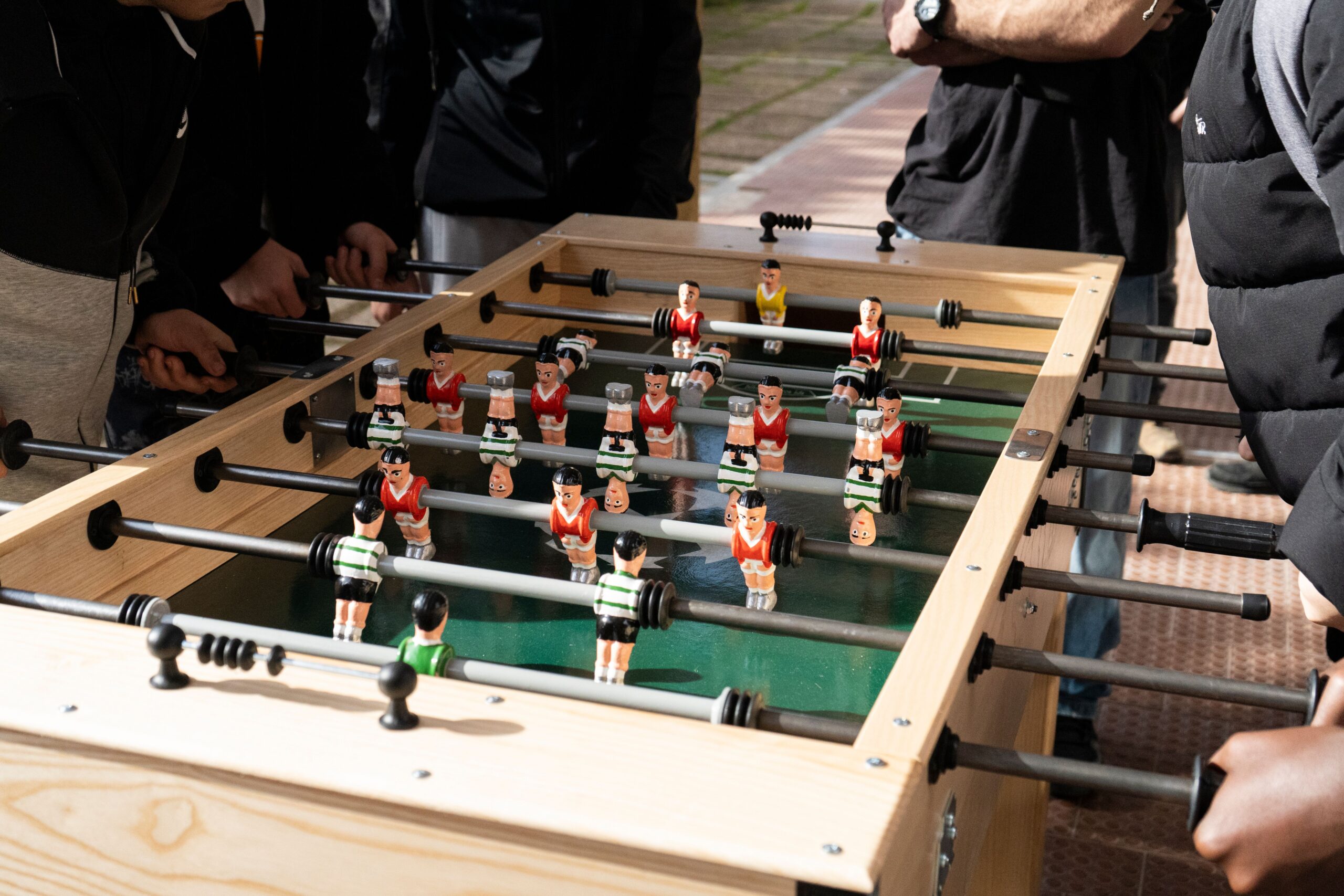 People playing a wooden foosball table outdoors
